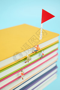 在一叠彩色书本上攀登的微距小人图片