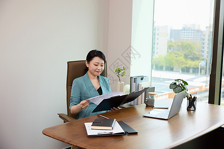 一位商务女性坐在办公室翻看文件图片
