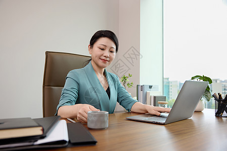 女白领坐在办公室电脑前喝咖啡图片