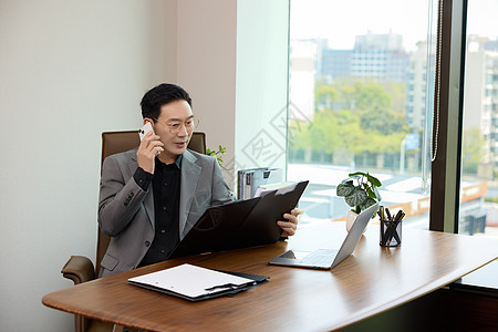 一位男白领坐在办公室打电话图片