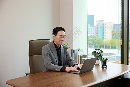 在办公室对着电脑工作的男白领形象图片