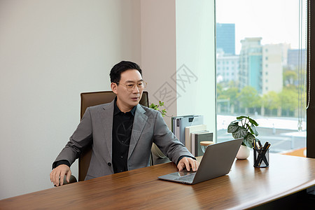 在办公室对着电脑工作的男白领形象图片