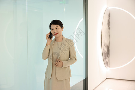 女白领在公司大楼走廊拿着手机打电话图片