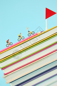 彩色书籍上骑行的创意微距小人图片