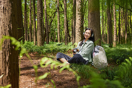 坐在森林里带耳机听歌放松的女孩图片