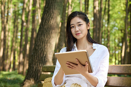 坐在森林长椅上画画的女孩图片