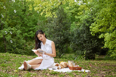 坐在草地上看书的女孩图片