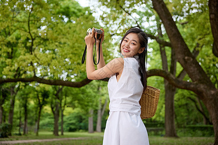 在森林里拿着相机拍照的女孩形象图片