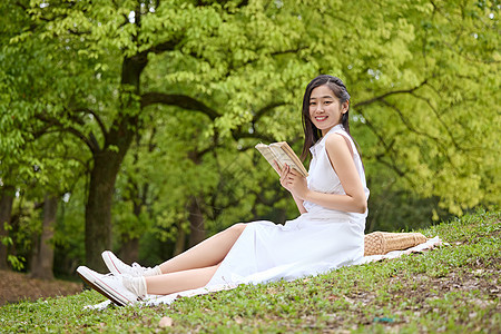 户外公园草坪上看书的美女图片