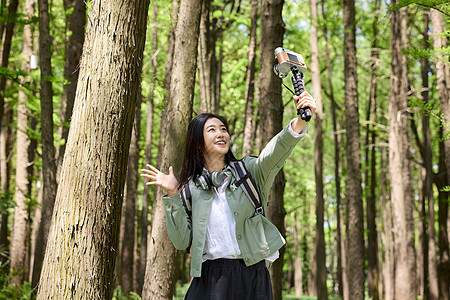 森林里美女用自拍杆和大树合影图片