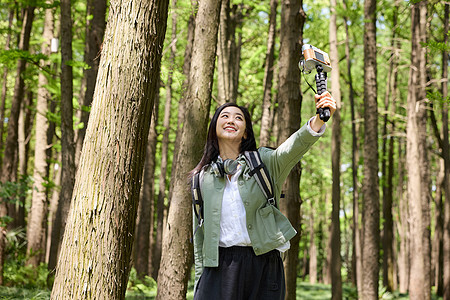 森林里美女用自拍杆和大树合影图片