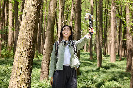 森林里美女用自拍杆和大树合影图片