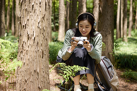 公园里美女蹲在地上用相机拍摄植物图片