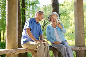 坐在公园亭子下对着手机笑的老年夫妇秒视频