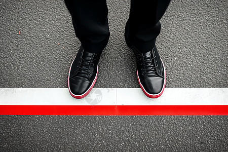 黑色鞋子站在红白线上图片