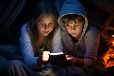 黑暗中两个孩子一起看着平板电脑背景
