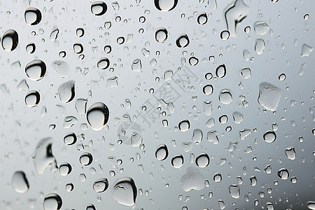 透明玻璃上滴落的雨滴图片