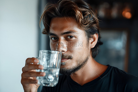 男子举着玻璃杯喝水图片