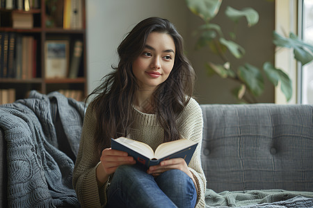 一个女人坐在客厅里读书背景图片