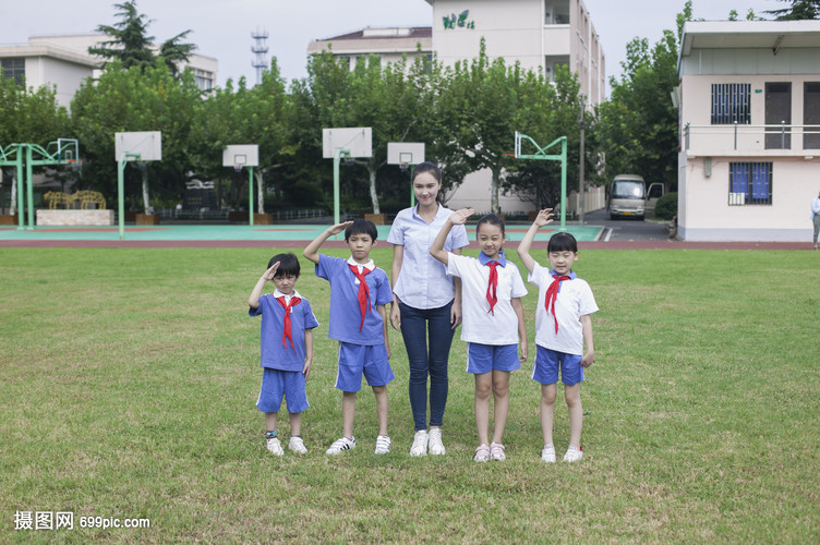 女老师和男女同学在操场上升国旗敬礼