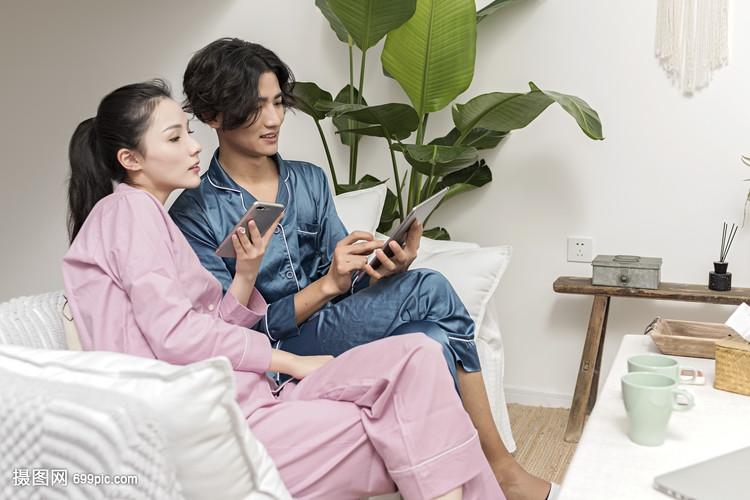 情侣在客厅休息玩手机平板电脑
