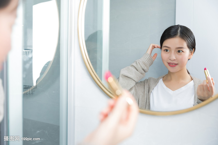 照着镜子画口红的年轻女性
