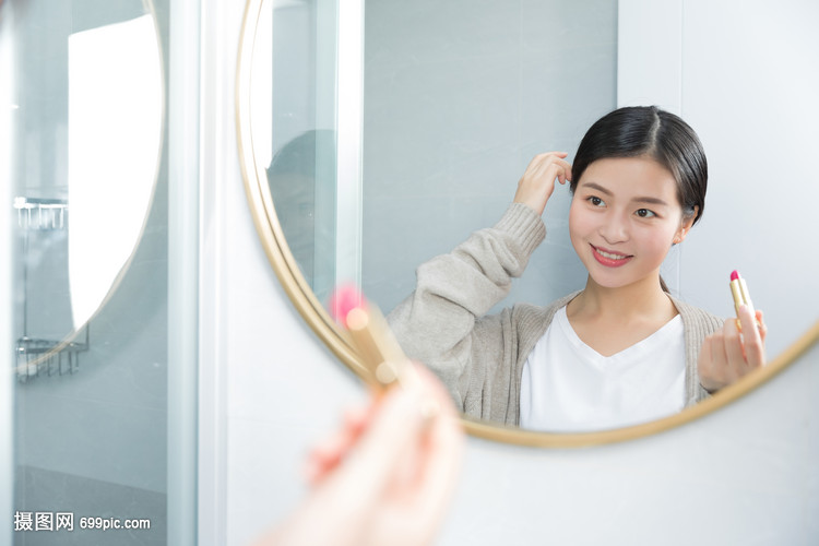 照着镜子画口红的年轻女性