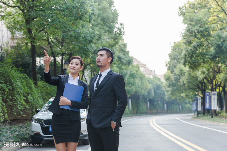 车旁商务女士给商务男士介绍房子