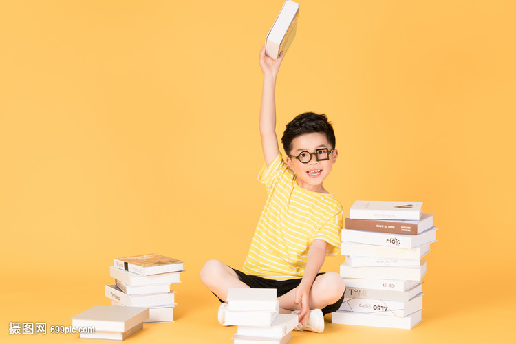 拿着书本坐在书旁的快乐男孩