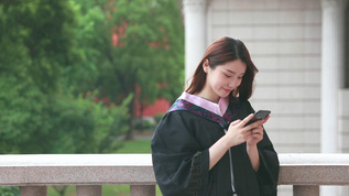 穿毕业装的女学生低头看手机视频素材