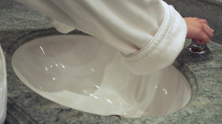 白浴袍中的妇女将水龙头和洗手视频素材