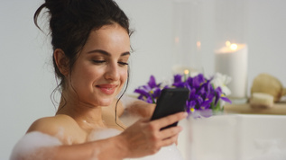 女性在浴缸里用智能手机接收信息视频素材