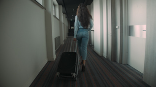 年轻女子在旅馆走廊上拉着行李箱视频素材