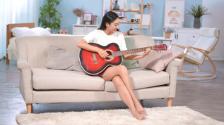 4k居家女生坐在沙发弹吉他视频素材