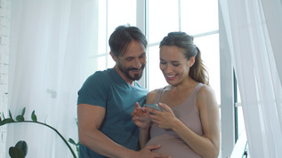 丈夫陪着怀孕的妻子一起看手机视频素材