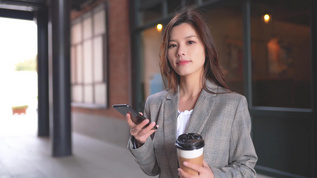 咖啡馆前的职场女生在玩手机喝咖啡视频素材