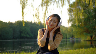 户外河边听音乐的女青年视频素材