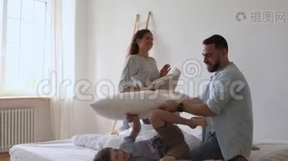 快乐的年轻父母打着躺在床上的小孩子抱着枕头。mov格式视频下载_正版视频编号2465769-摄图网