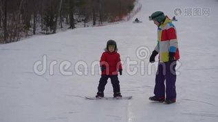 年轻人滑雪板教练教小男孩如何骑滑雪板。 冬季活动概念mov格式视频下载_正版视频编号3442943-摄图网