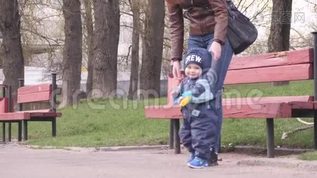 一个年轻的女人和她的小男孩抱着小铲子走在城市公园里，在一个春天的阴天和孩子mov格式视频下载_正版视频编号2846634-摄图网