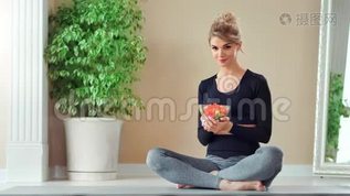 微笑的运动女人摆姿势坐在莲花的位置，拿着盘子和新鲜蔬菜沙拉mov格式视频下载_正版视频编号1271948-摄图网