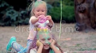 两个小女孩姐妹，一个十几岁的女孩和一个小女孩躺在草坪上，在公园里玩和洒彩色沙子mov格式视频下载_正版视频编号2547995-摄图网