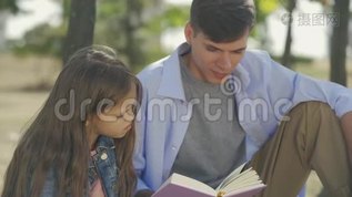 一个十几岁的小男孩和他的小妹妹一起看书，在阳光明媚的秋日里坐在公园里，写着诗或故事mp4格式视频下载_正版视频编号1648325-摄图网