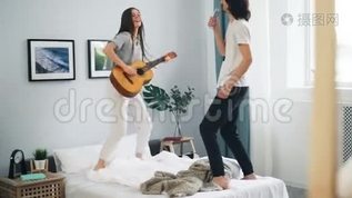 快乐的学生在家里用遥控器唱歌，弹吉他在床上跳舞mov格式视频下载_正版视频编号826714-摄图网