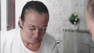 年轻女子正在浴室的镜子前洗脸。mov格式视频下载_正版视频编号978620-摄图网