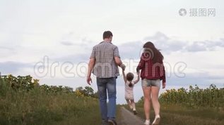 小女儿跳着手牵着爸爸妈妈。 一家人带着小孩走在路上，在田野旁欢笑mov格式视频下载_正版视频编号2704465-摄图网
