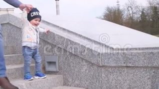 戴墨镜的大胡子牵着他的小儿子的手，帮助快乐的小男孩沿着花岗岩阶梯mov格式视频下载_正版视频编号1954279-摄图网