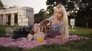 金发碧眼的女人躺在公园的一块地上，躺在一个格子的垃圾上，抚摸着她的小狗。 背景模糊mov格式视频下载_正版视频编号1282393-摄图网