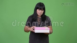 美丽的超重亚洲女人打开礼品盒，看上去很惊讶mov格式视频下载_正版视频编号1509473-摄图网