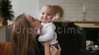 妈妈抱着宝宝，孩子微笑着看着心爱的妈妈.. 圣诞节时一起站在白色的厨房里mov格式视频下载_正版视频编号1584855-摄图网